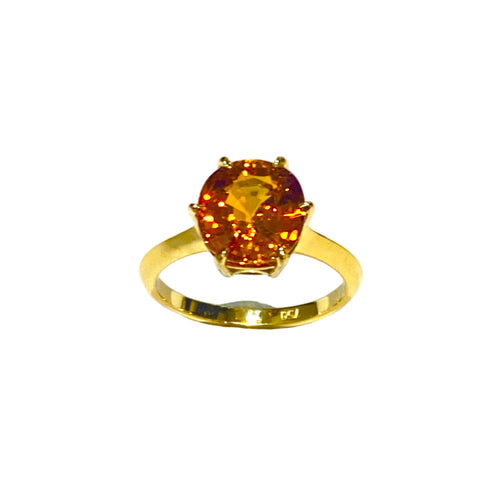 Gold ring with a large amber-colored gemstone on a white background